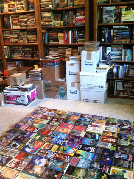 Running out of shelf space, John begins to carpet his floor with books.